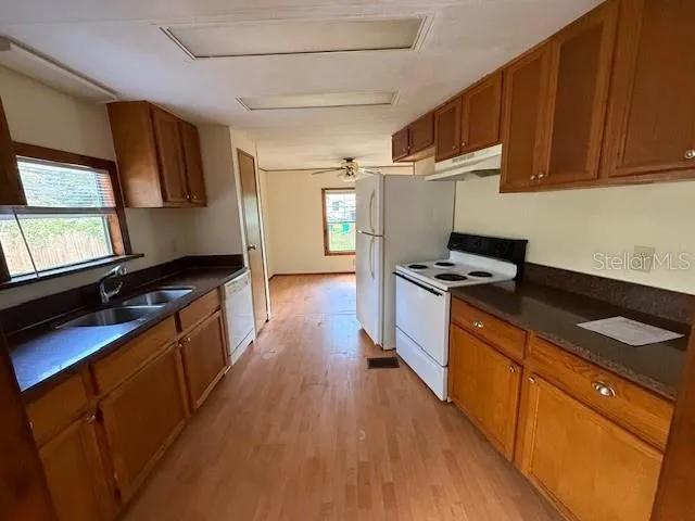 a kitchen with granite countertop stainless steel appliances cabinets a sink and a wooden floor