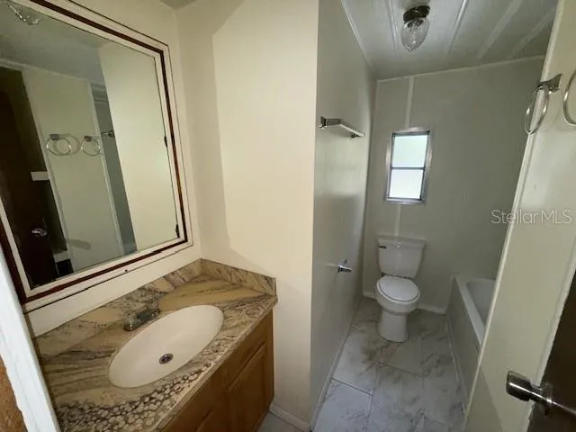 a bathroom with a granite countertop sink and mirror with toilet