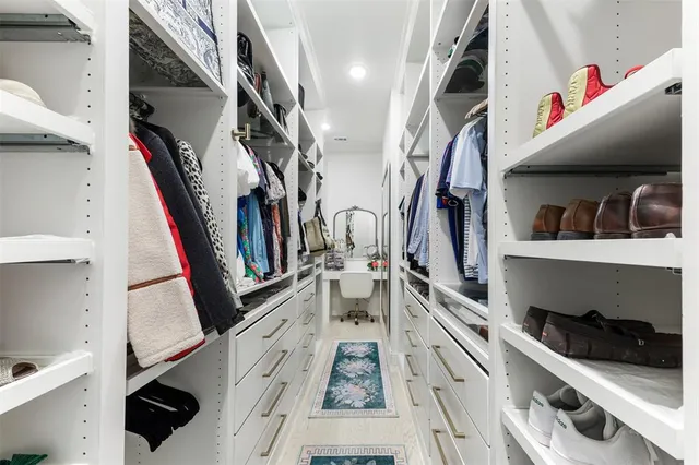 a view of walk in closet with clothes and shoes