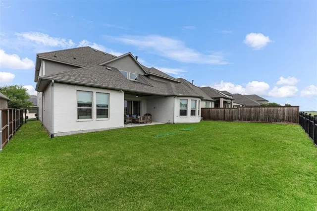 a view of a yard in front of a house with plants and large tree