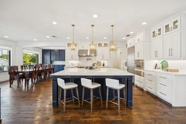 a large kitchen with kitchen island a island a sink a stove and a dining table with chairs