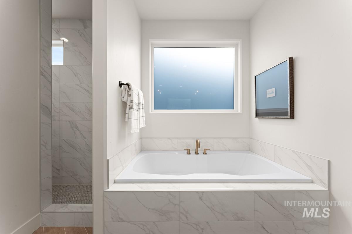 13338 North Spring Creek Way Boise, ID 83714 - Photo 20 of 46 Built-in soaking tub with bronze-finish fixtures, surrounded by white marble-look tile