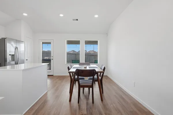 a kitchen with a dining table chairs and wooden floor