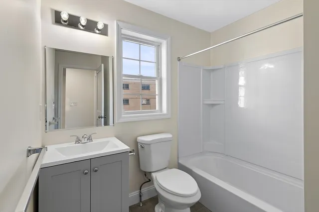 a bathroom with a bathtub shower sink mirror and toilet