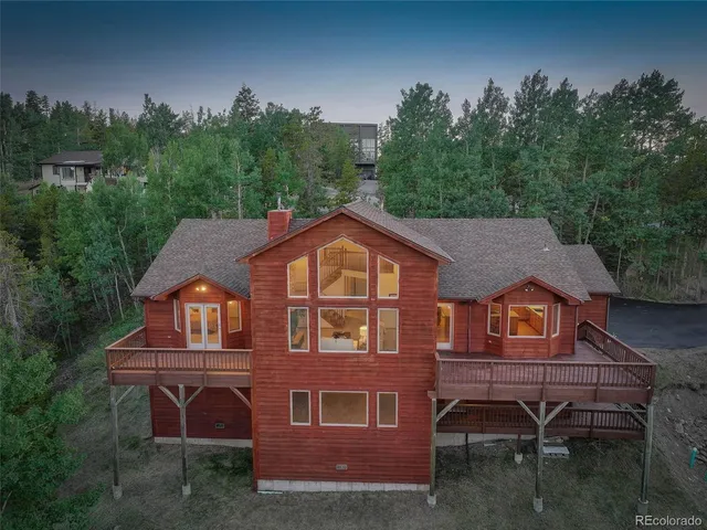 a view of a house with a yard plants and large tree