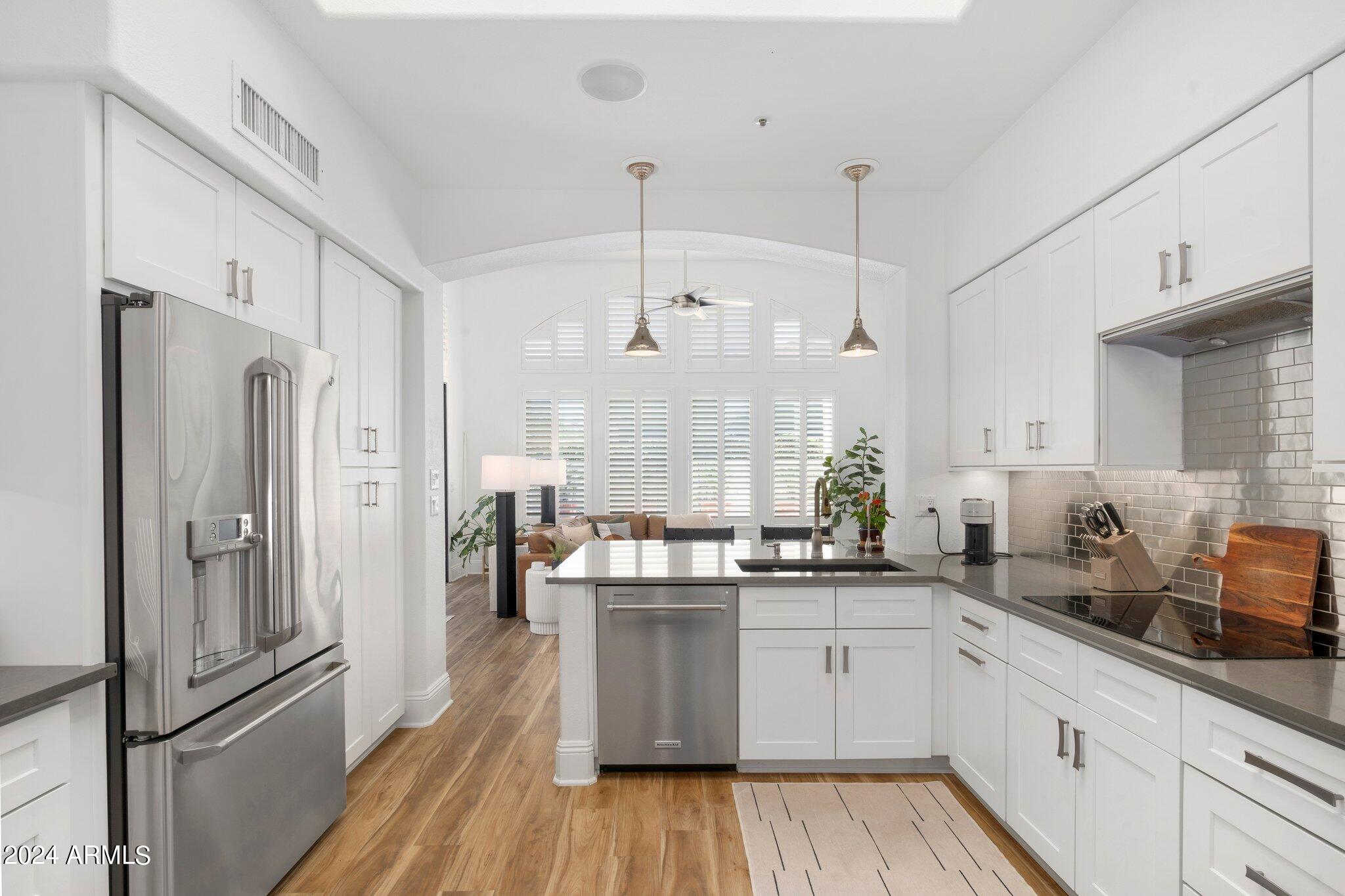 7705 East Doubletree Ranch Road, Unit 38 Scottsdale, AZ 85258 - Photo 11 of 31 a kitchen with stainless steel appliances a refrigerator a sink dishwasher a oven and white cabinets with wooden floor