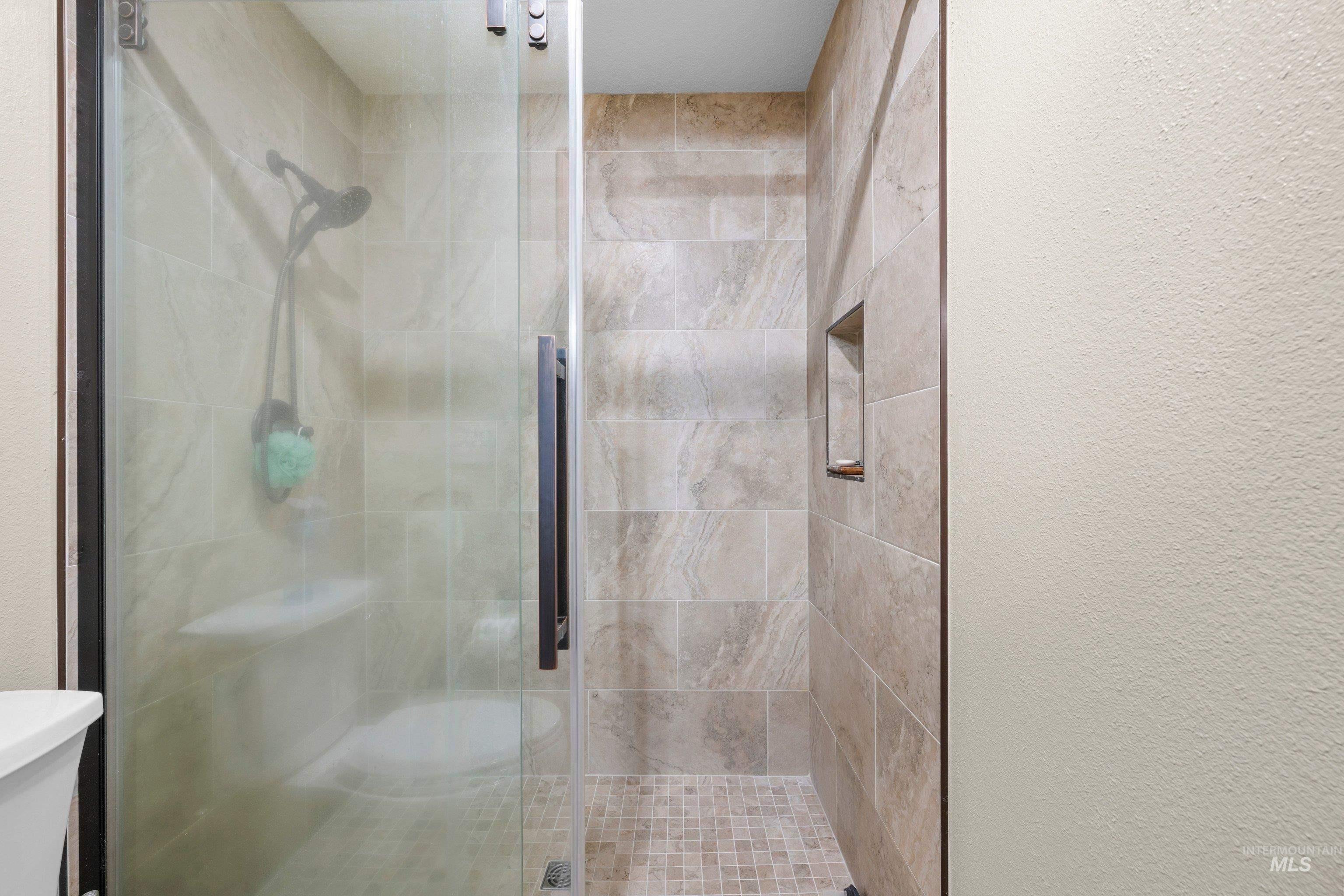 1921 Incline Way Meridian, ID 83646 - Photo 30 of 50 Enclosed shower with a clear glass panel door, dark-toned hardware, and a built-in shower niche