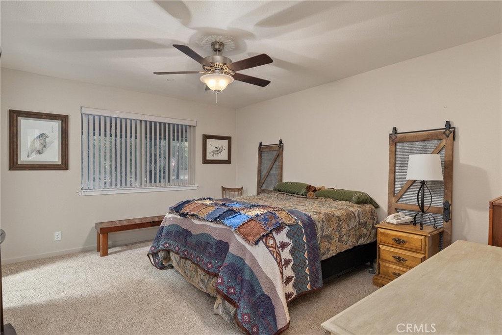7528 Humboldt Road Butte Meadows, CA 95942 - Photo 19 of 41 a bedroom with a bed a chandelier and a dresser