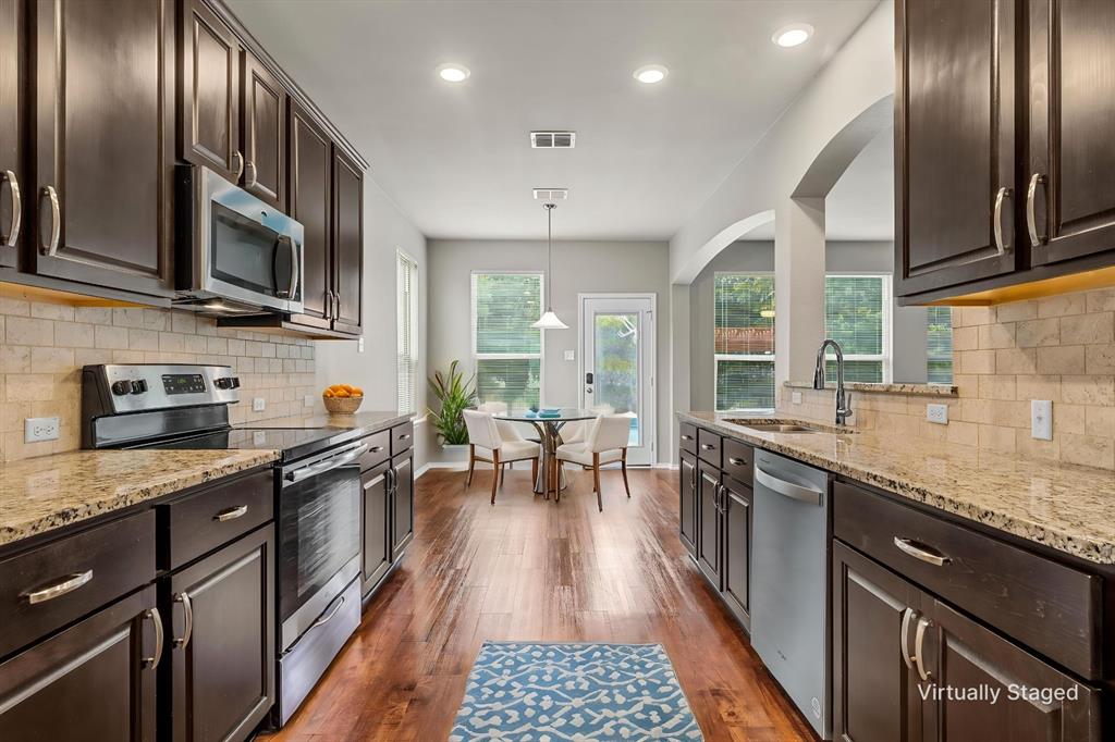202 Milky Way Road Bruceville, TX 76630 - Photo 13 of 39 a kitchen with stainless steel appliances granite countertop a stove top oven a sink dishwasher a dining table and chairs with wooden floor