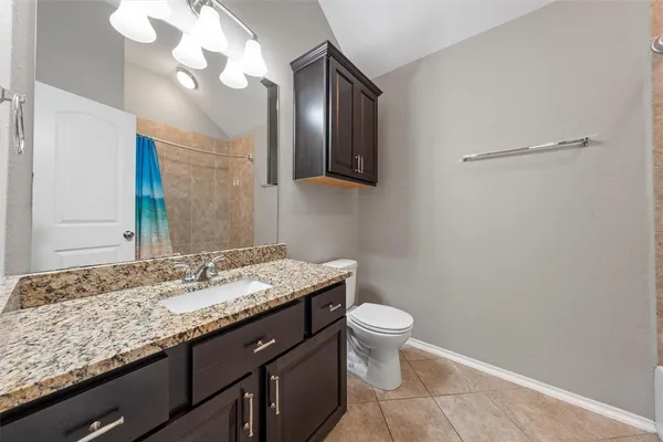 a bathroom with a granite countertop sink a toilet and a mirror