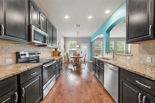 a kitchen with stainless steel appliances granite countertop lots of counter space wooden floor and stainless steel appliances