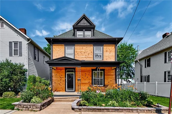 a house with a clock on the wall next to a yard