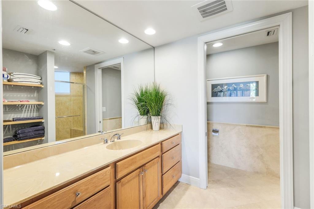 265 Indies Way, Unit T02 Naples, FL 34110 - Photo 22 of 38 a bathroom with a sink a large mirror and a shower