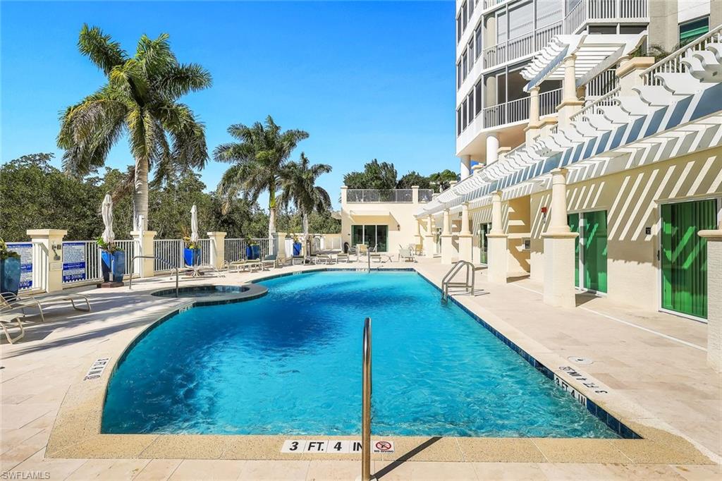 265 Indies Way, Unit T02 Naples, FL 34110 - Photo 27 of 38 a view of a swimming pool with a lawn chairs under palm trees