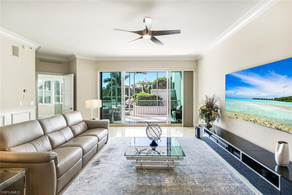 265 Indies Way, Unit T02 Naples, FL 34110 - Photo 5 of 38 a living room with couch floor to ceiling window and a flat screen tv