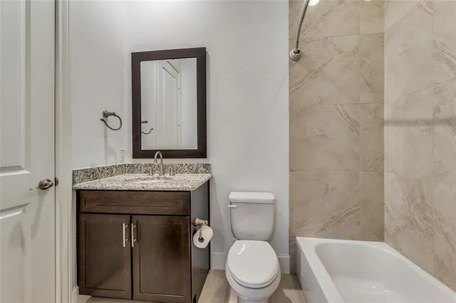 a bathroom with a granite countertop toilet sink and mirror