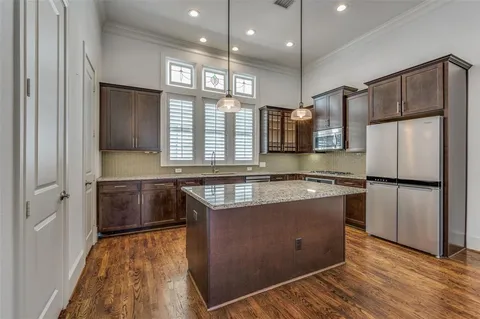 a kitchen with stainless steel appliances granite countertop a refrigerator a sink dishwasher a stove and white countertops with wooden floor