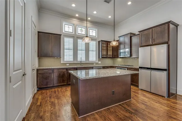 a kitchen with stainless steel appliances granite countertop a refrigerator a sink dishwasher a stove and white countertops with wooden floor