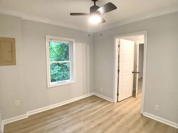 a view of an empty room with wooden floor and a window