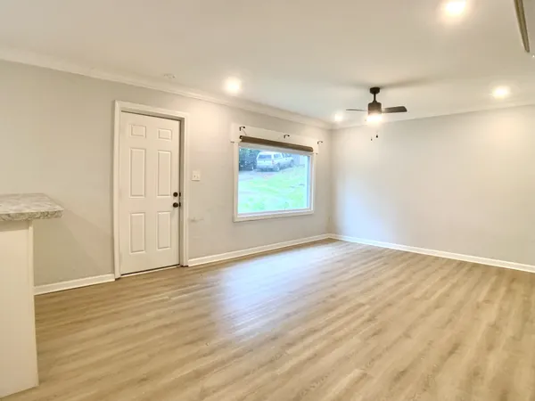 an empty room with wooden floor cabinet and windows