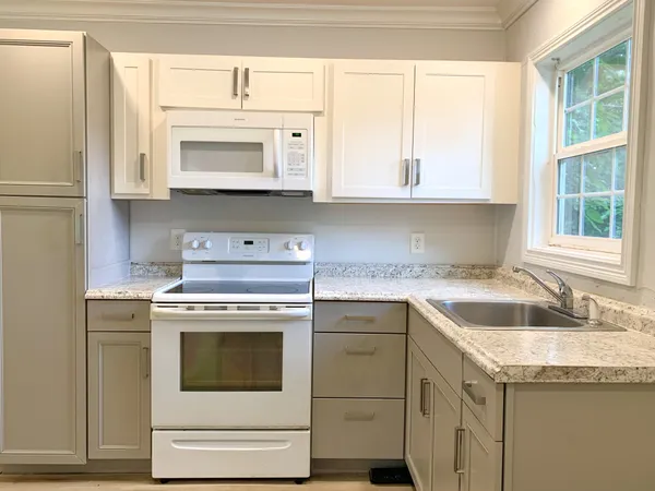a kitchen with granite countertop a sink stove and cabinets