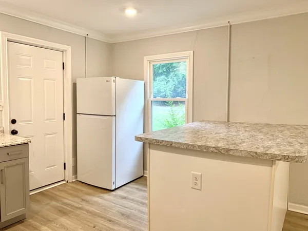 a kitchen with kitchen island granite countertop appliances a refrigerator a sink and a window