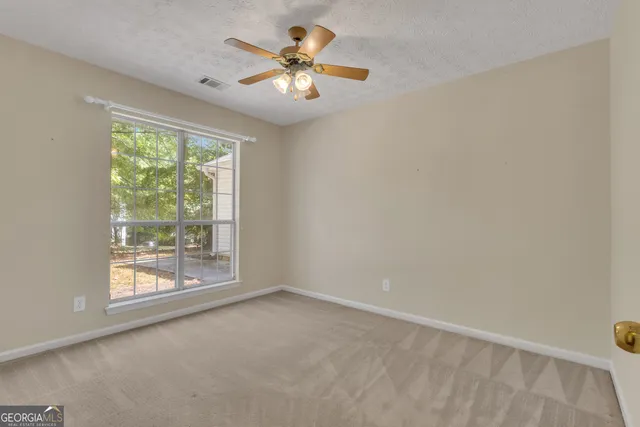 a view of an empty room and chandelier fan