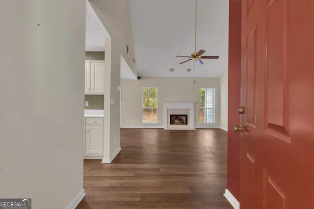an empty room with wooden floor fireplace and windows