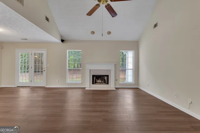 an empty room with wooden floor fireplace and windows