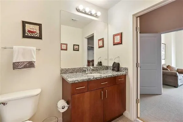 a bathroom with a granite countertop sink mirror vanity and toilet