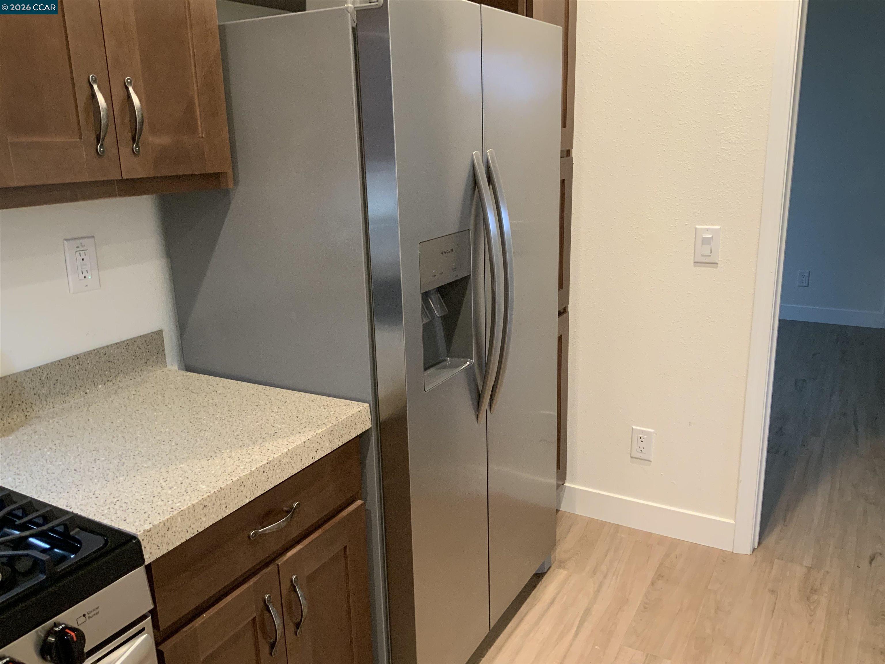 65 Pali Way Pittsburg, CA 94565 - Photo 10 of 32 a kitchen with metallic refrigerator and wooden cabinets