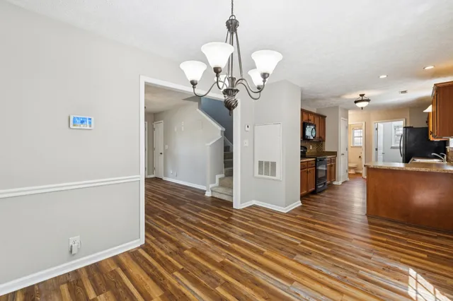 a kitchen with stainless steel appliances granite countertop a stove top oven a sink dishwasher a dining table and chairs with wooden floor