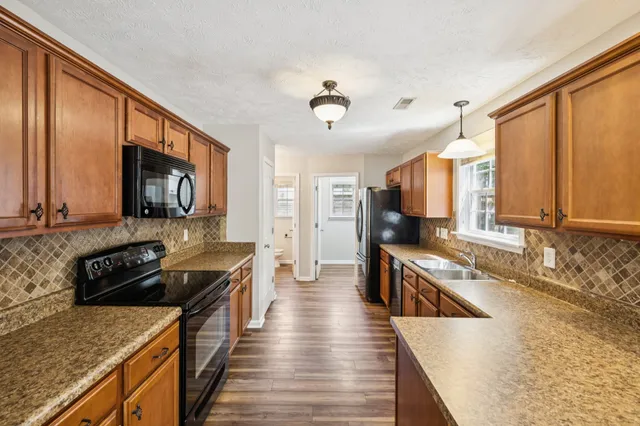 a kitchen with stainless steel appliances granite countertop a sink and wooden cabinets