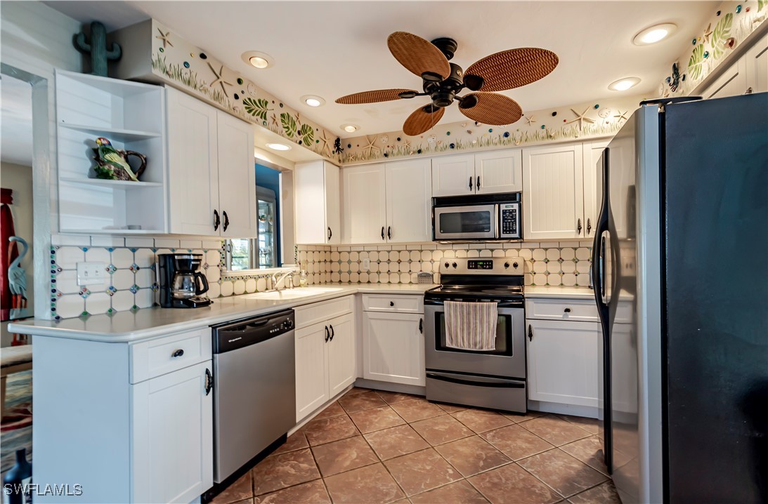 12101 Moon Shell Drive Matlacha Isles, FL 33991 - Photo 11 of 42 a kitchen with stainless steel appliances granite countertop a refrigerator a stove a microwave oven a sink with island and chairs
