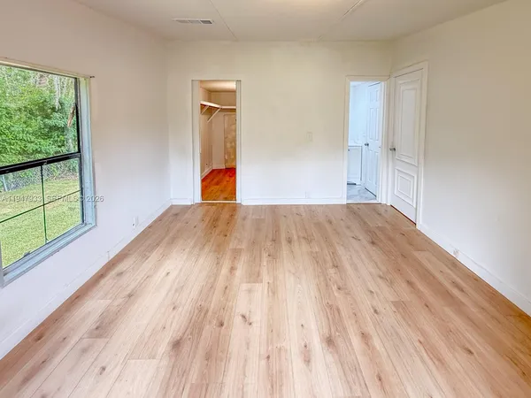 a view of empty room with wooden floor and fan