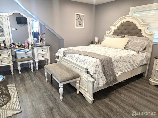 a bedroom with a bed a mirror and wooden floor