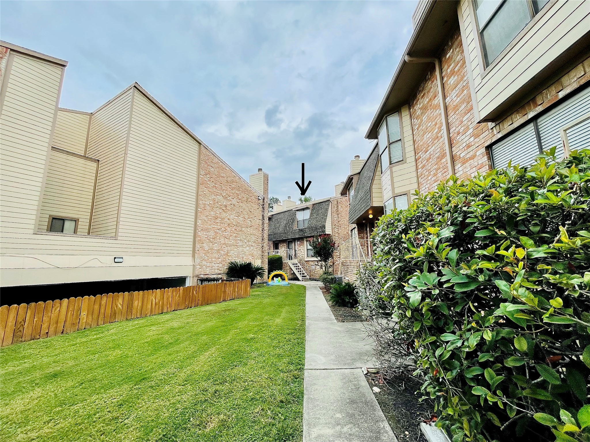 a backyard of a house with lawn chairs plants and large tree