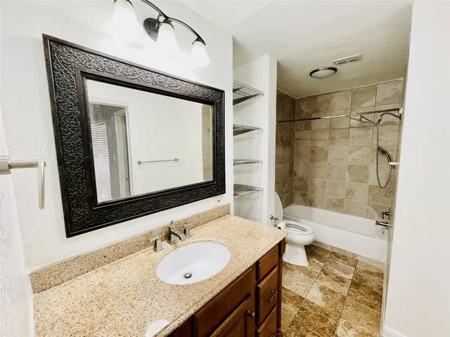 a bathroom with a granite countertop sink mirror and a bathtub