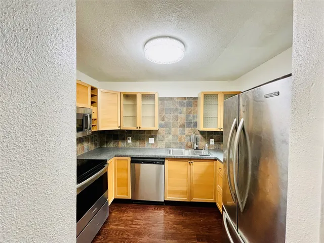 a kitchen with stainless steel appliances granite countertop a refrigerator a sink dishwasher a stove with wooden floor and cabinets