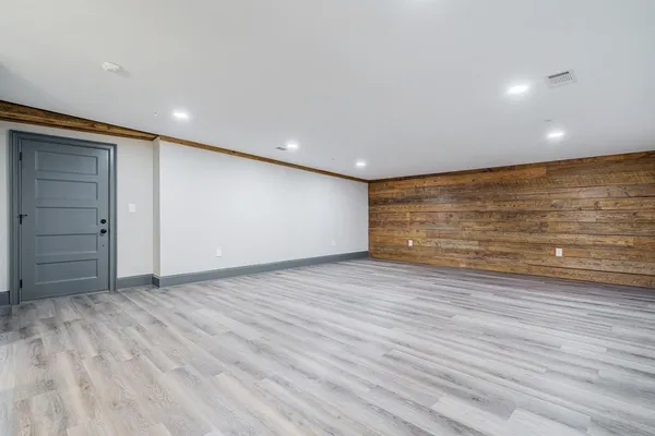 a view of an empty room with wooden floor and a kitchen