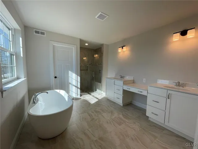 a bathroom with a tub sink double vanity and tub