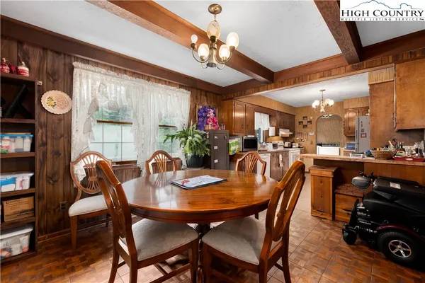 a view of a dining room with furniture a chandelier and large window