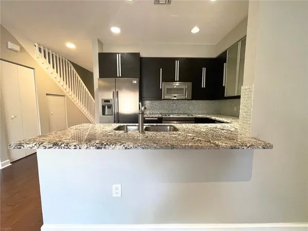 a kitchen with kitchen island granite countertop a sink and cabinets