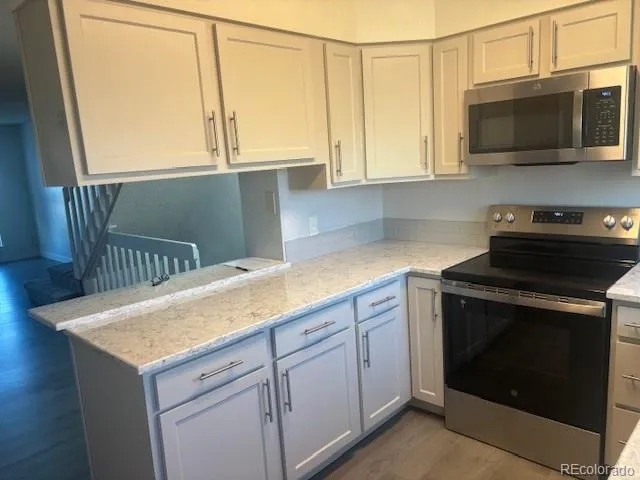 a kitchen with stainless steel appliances granite countertop a stove a microwave and white cabinets