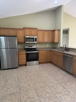 a kitchen with stainless steel appliances granite countertop a sink and a refrigerator