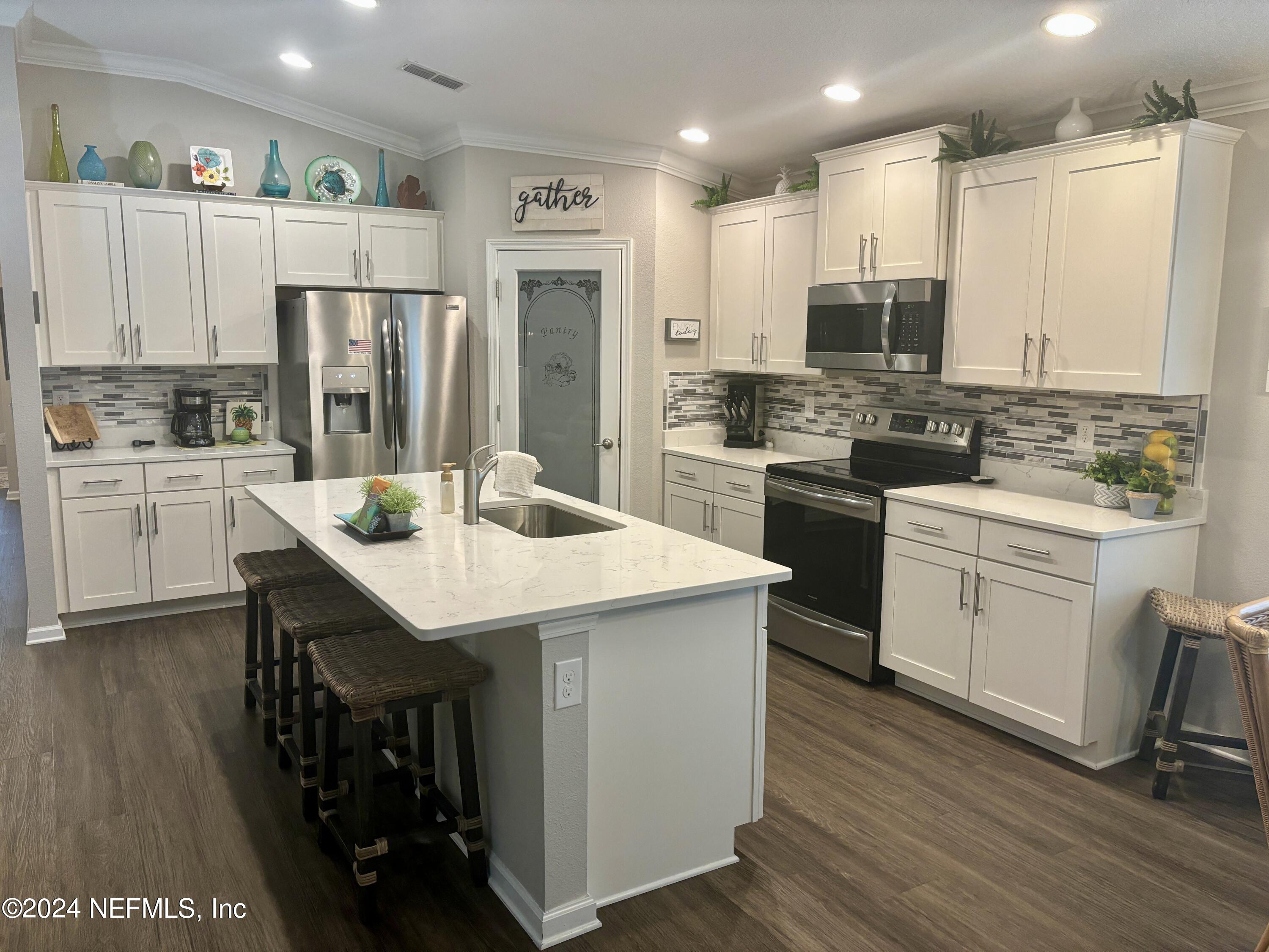 277 Palace Drive St. Augustine, FL 32084 - Photo 5 of 36 a kitchen with stainless steel appliances a sink a stove a refrigerator cabinets and wooden floor