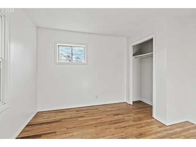 a view of an empty room with wooden floor and closet