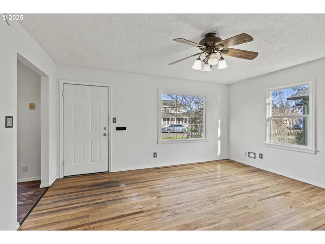a view of an empty room with wooden floor and a window
