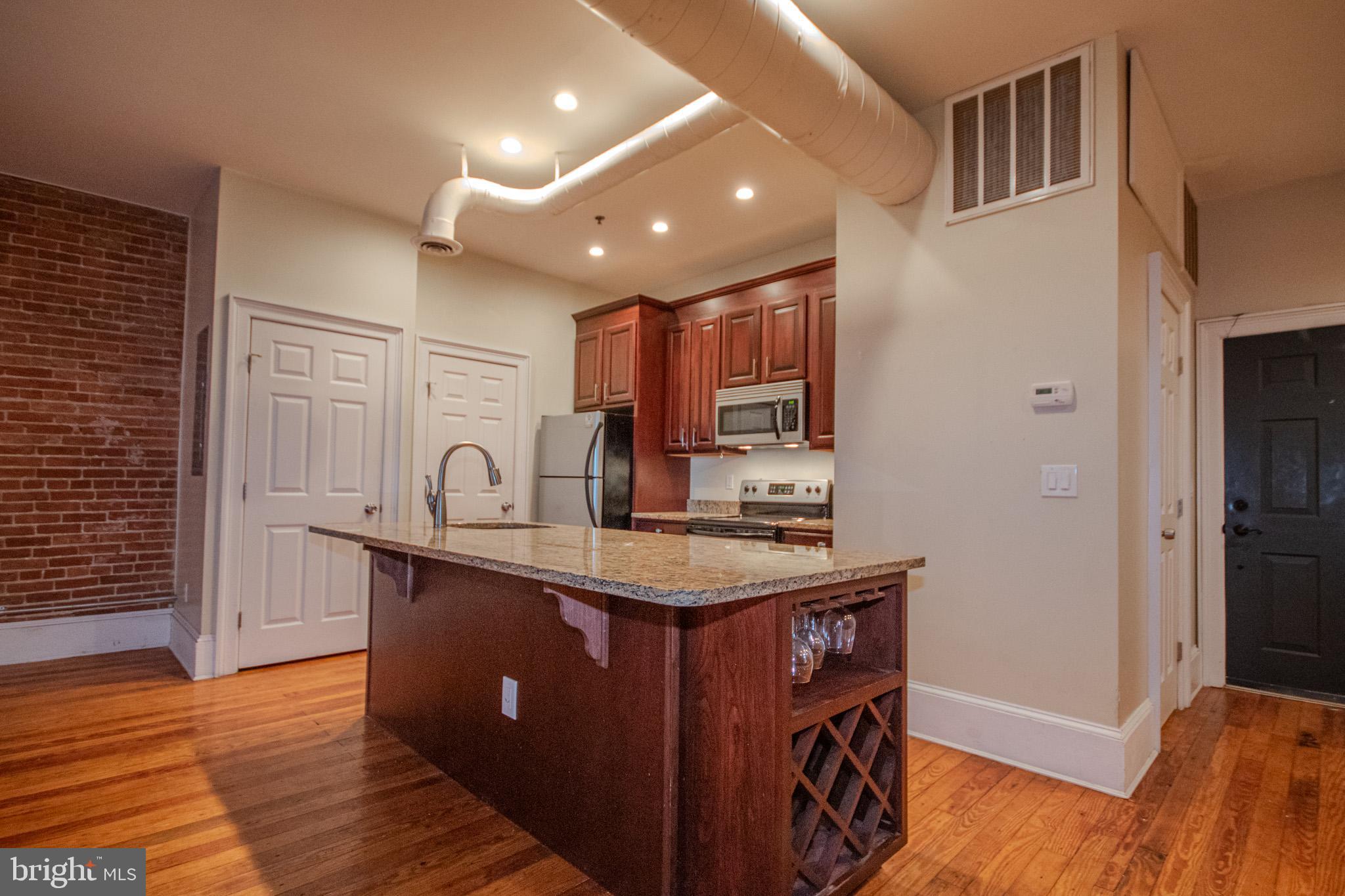 224 West Main Street, Unit 203 Salisbury, MD 21801 - Photo 5 of 20 a kitchen with kitchen island a sink appliances and cabinets