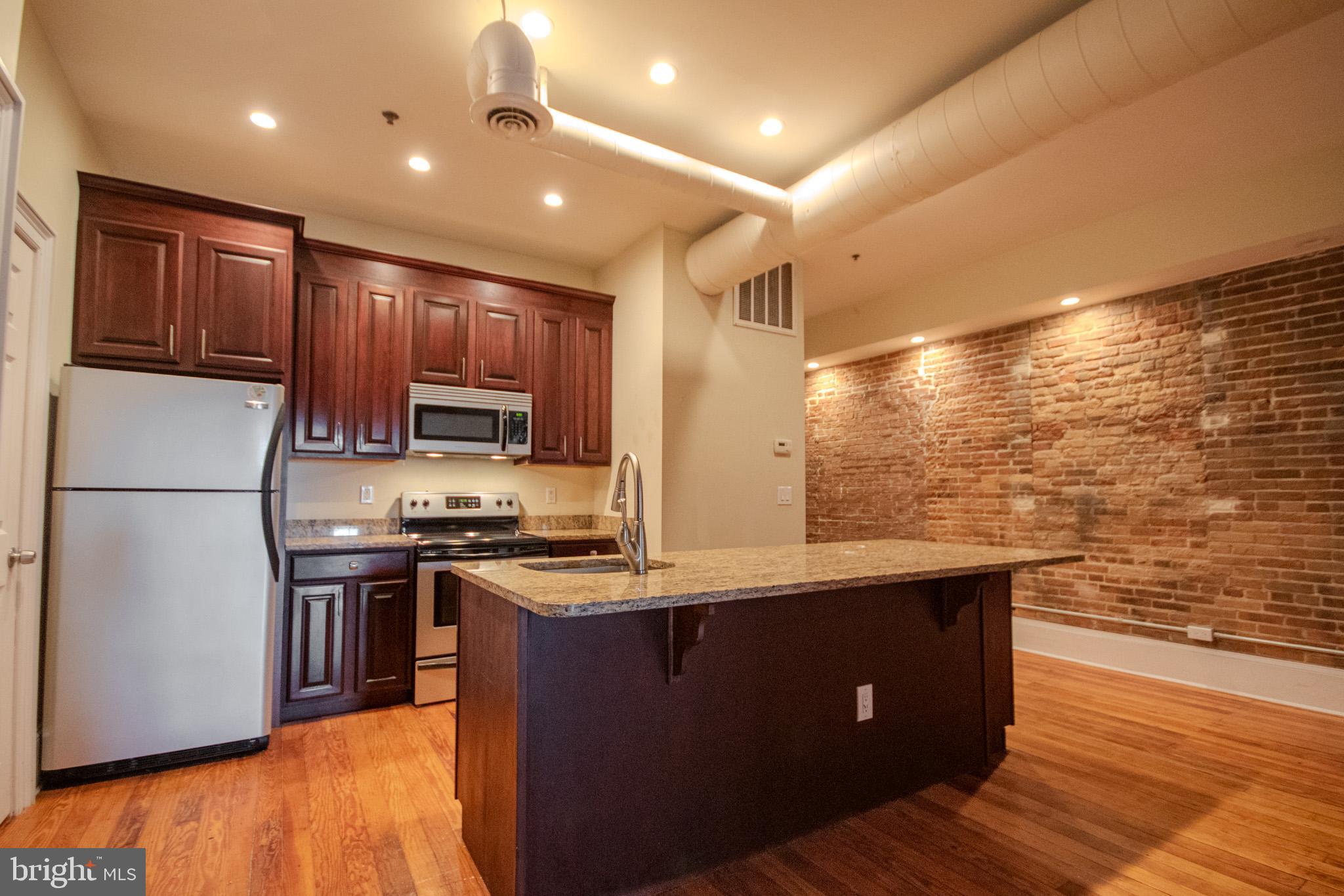 224 West Main Street, Unit 203 Salisbury, MD 21801 - Photo 20 of 20 a kitchen with stainless steel appliances granite countertop a refrigerator a stove and a sink with wooden floor